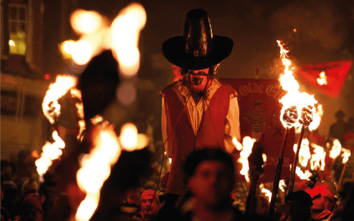 Guy Fawkes being carried through a parade with flaming torches